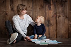 Mutter sitzt mit Kind im Arm auf dem Boden und sie schauen sich gemeinsam eine Landkarte an