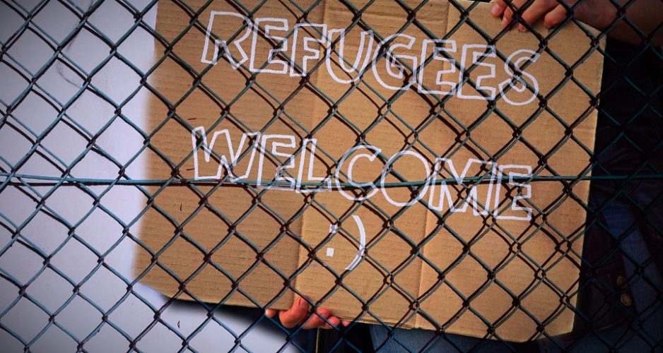 Schild hinter Gitterzaun mit dem Schriftzug "Refugees Welcome".